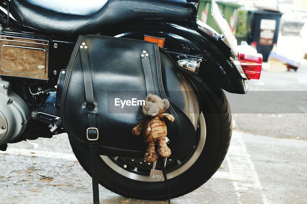 Stuffed toy hanging from motorcycle in parking lot