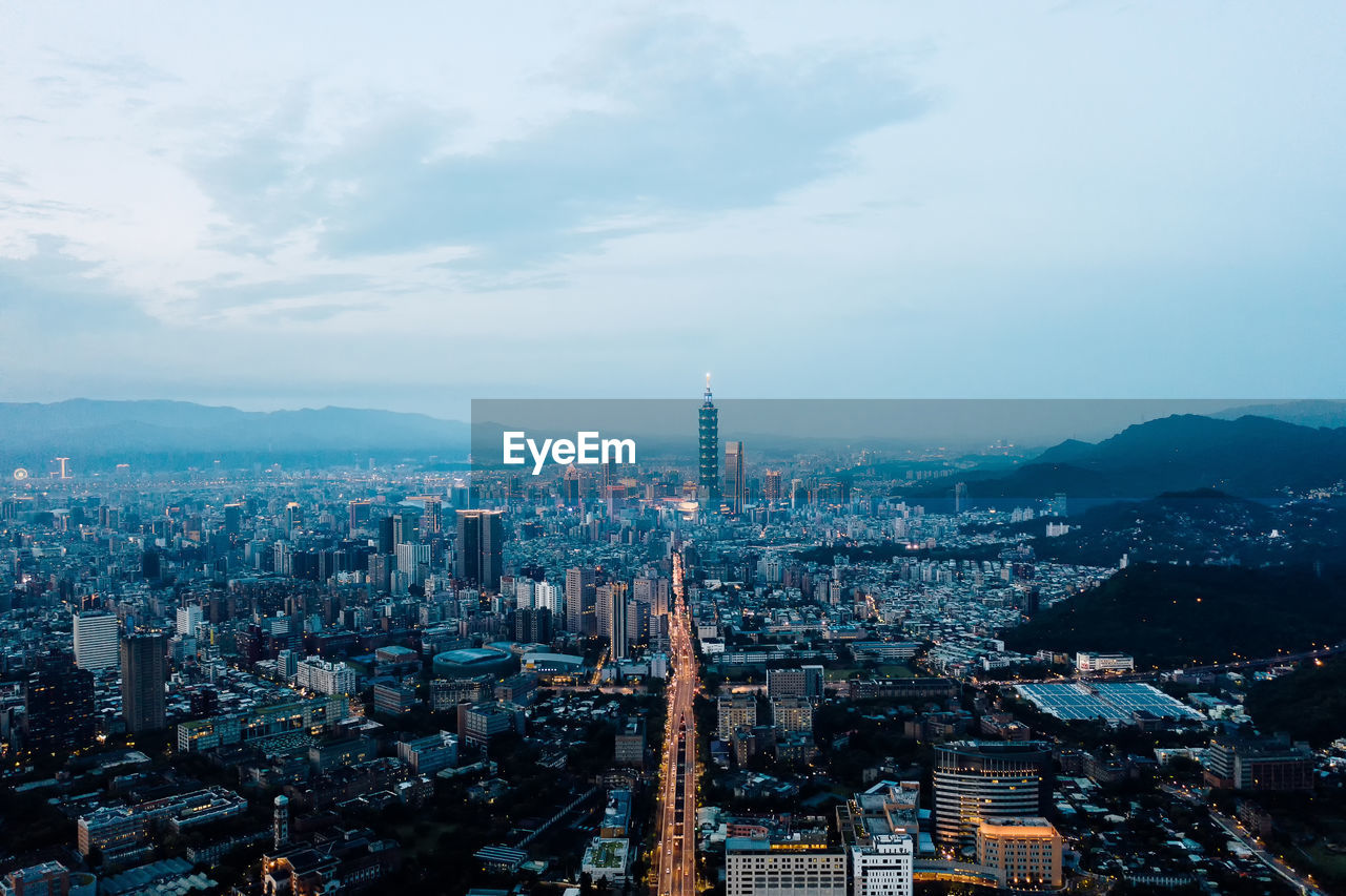 High angle view of city buildings against cloudy sky