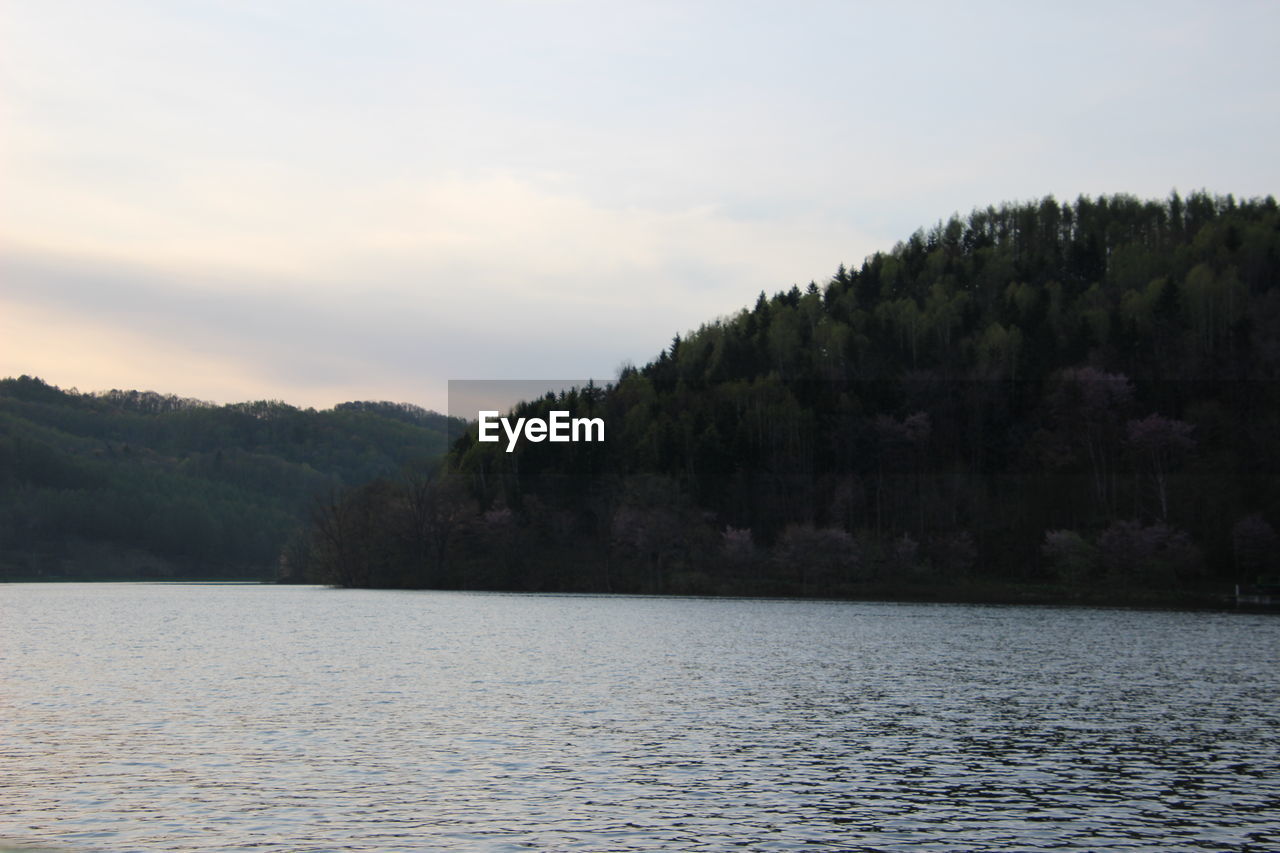 SCENIC VIEW OF LAKE BY TREE MOUNTAIN AGAINST SKY