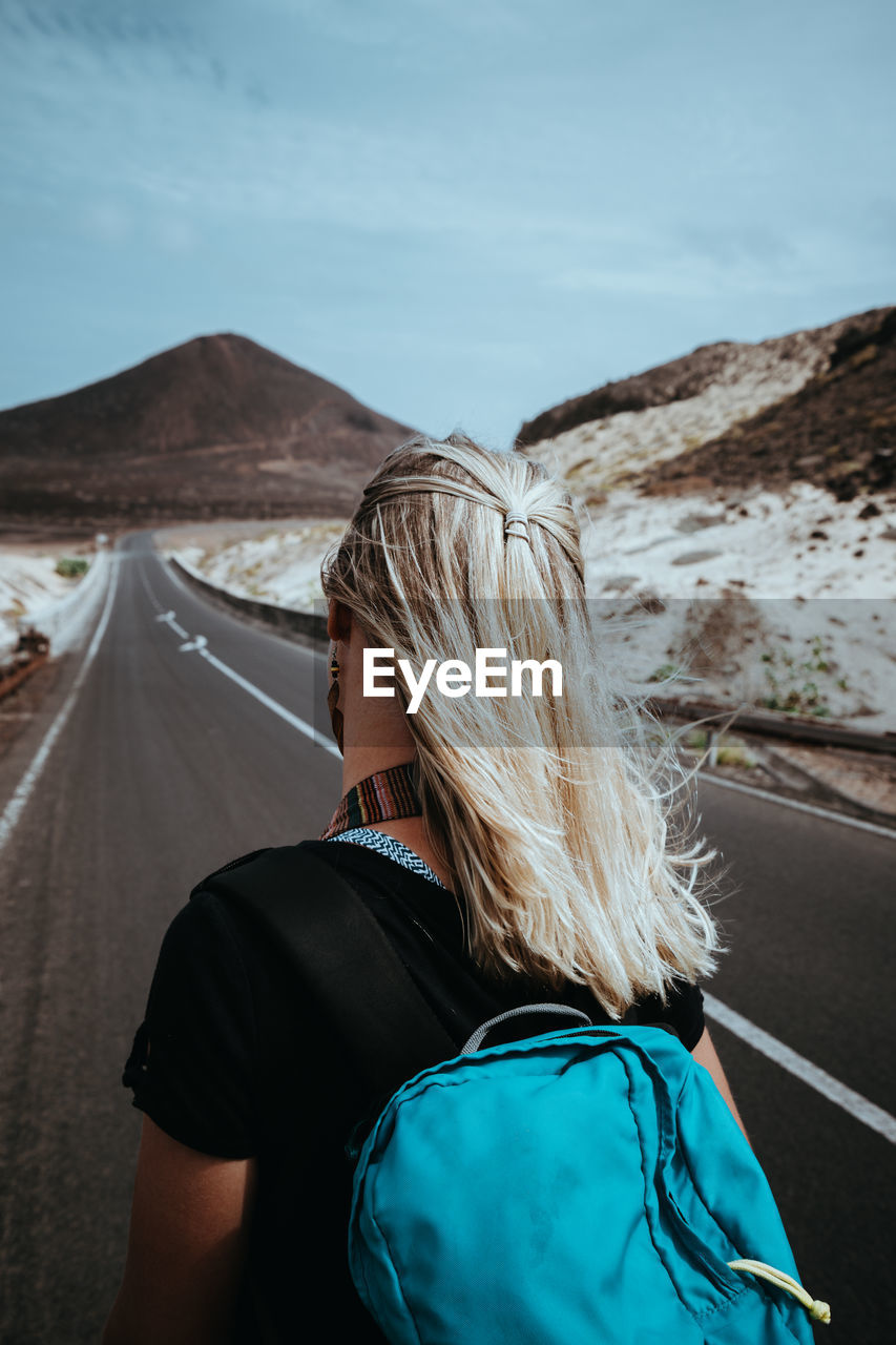 Woman traveler goes on desolate straight road over a surreal landscape. sao vicente cape verde