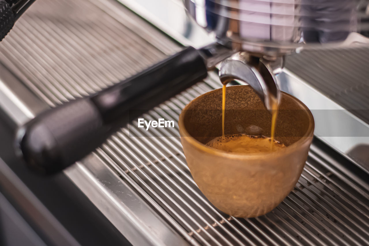 Preparing coffee with bar coffee machine, coffee is poured in a ceramic cup, close up