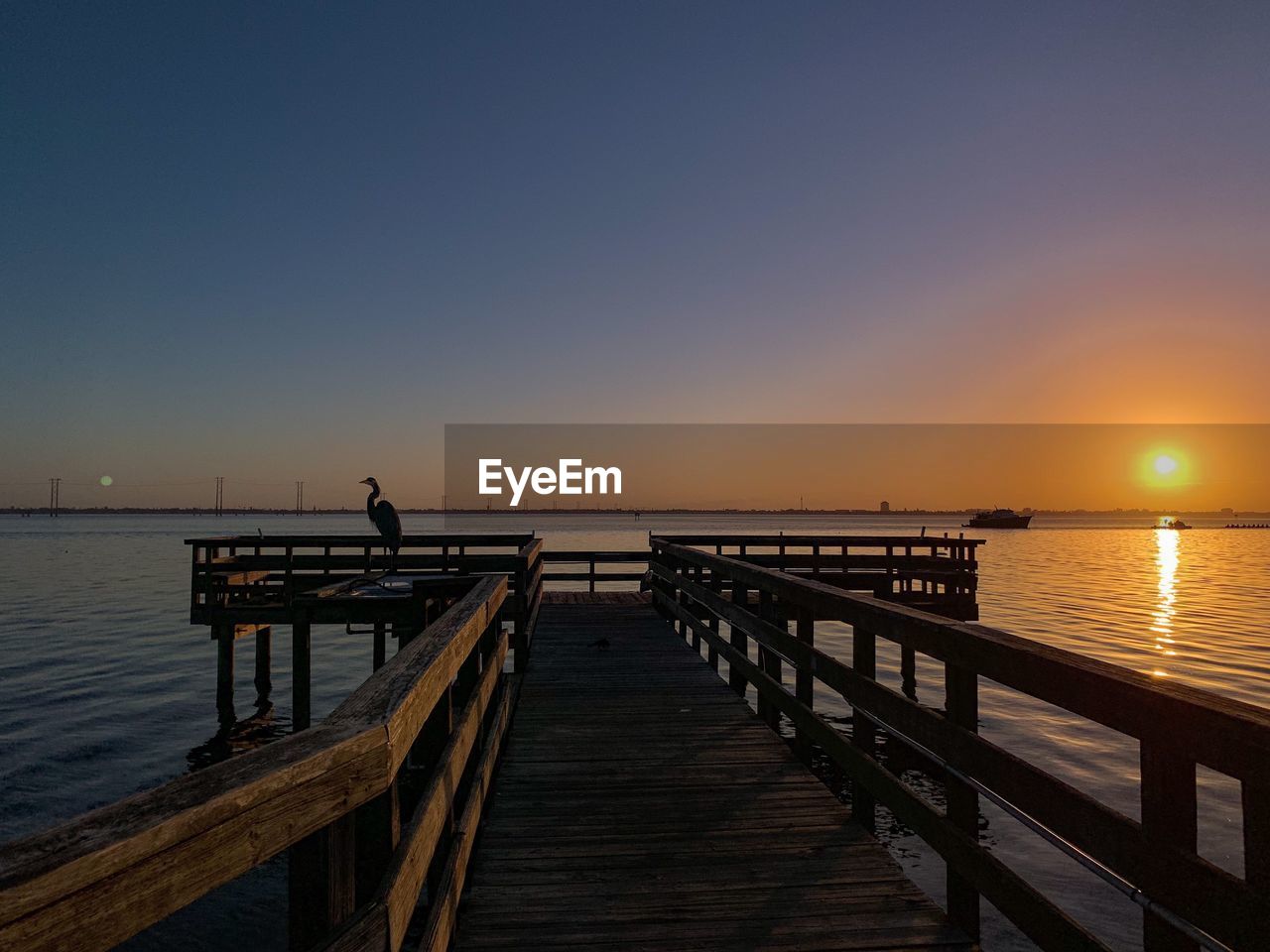 Silhouette pier on sea against clear sky during sunset