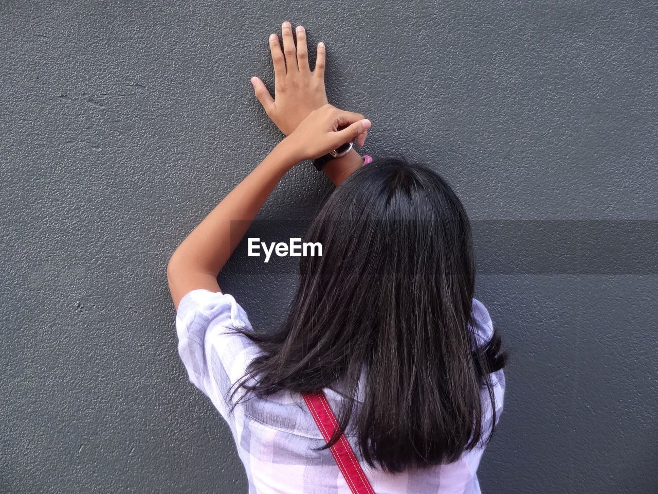 Rear view of woman leaning on wall