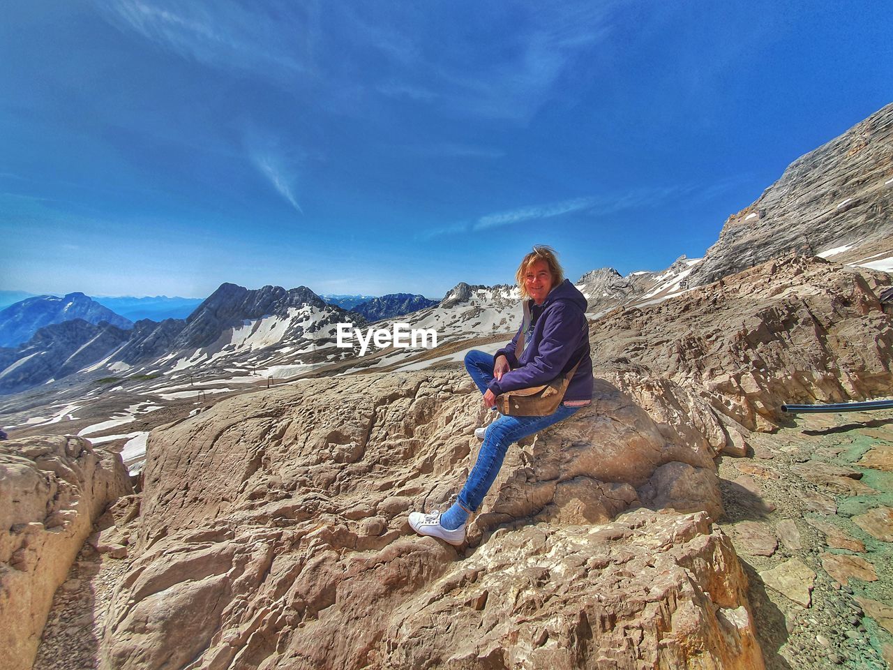 Full length of man sitting on rock against mountains
