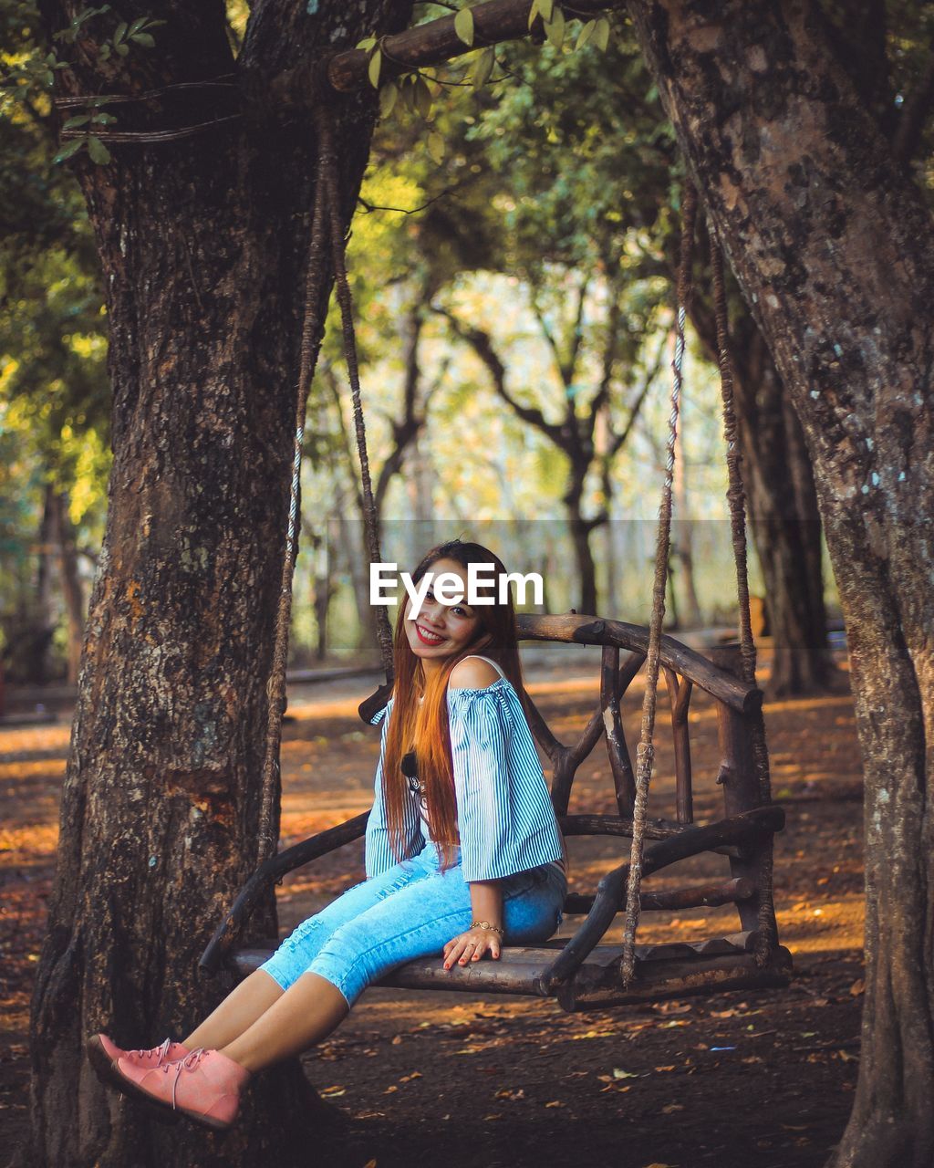 Full length portrait of woman sitting on swing in park