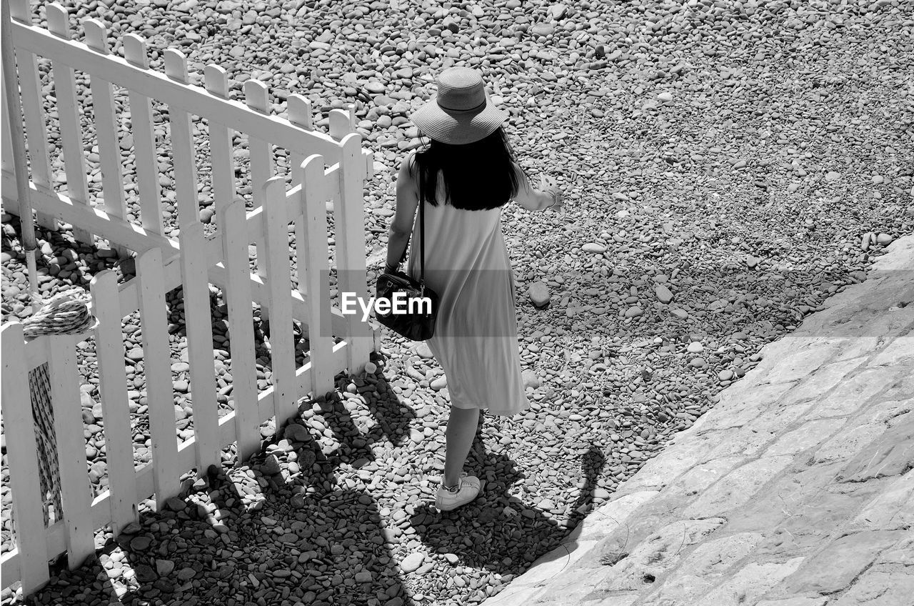 High angle view of woman walking by fence on field