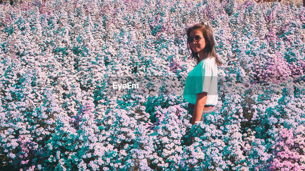 one person, spring, women, flower, standing, young adult, happiness, casual clothing, day, emotion, lifestyles, adult, smiling, flowering plant, nature, hairstyle, blue, multi colored, leisure activity, outdoors, female, front view, portrait, looking, child, person, long hair