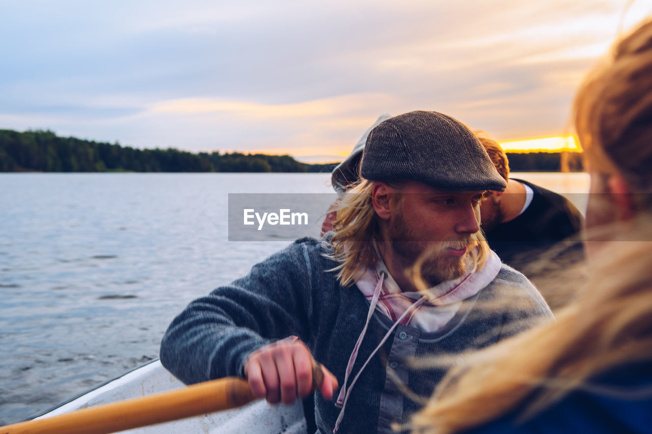 Man oaring boat in river during sunset