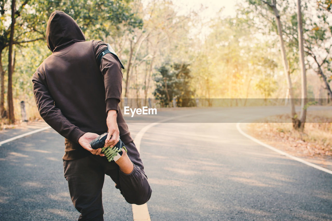 Man stretching leg on road