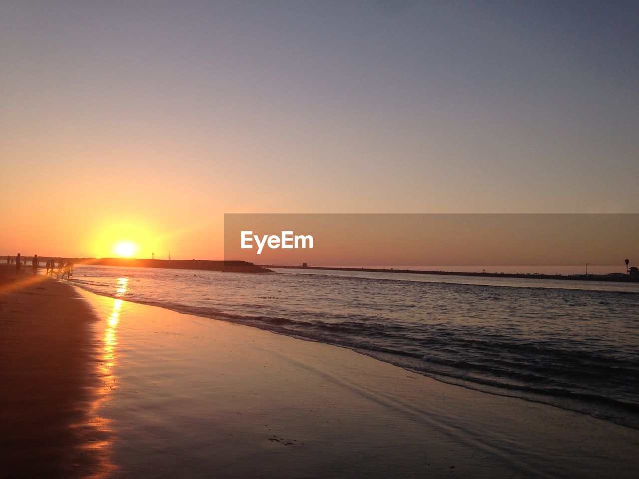 Scenic view of beach against sky at sunset