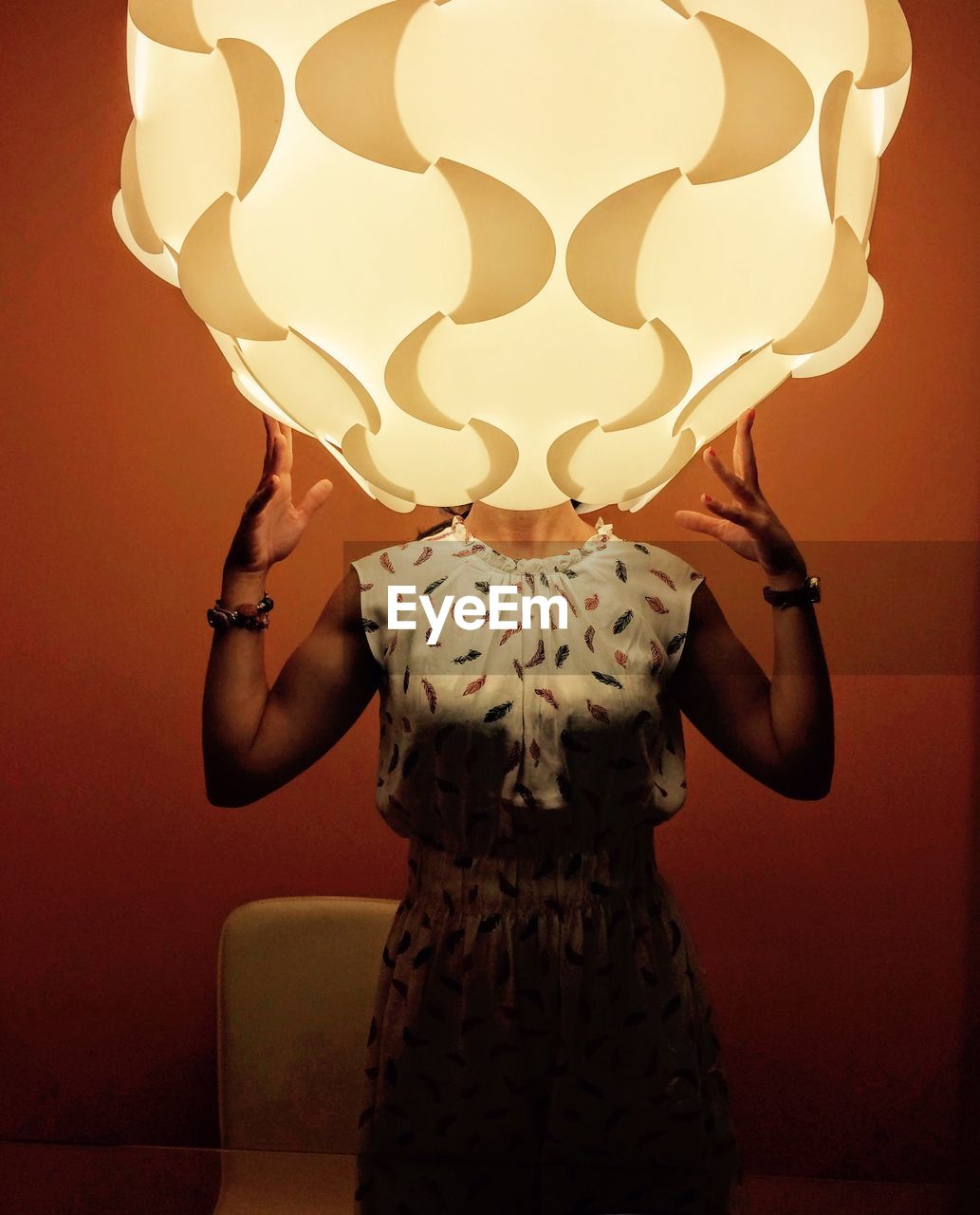 Woman standing with head inside illuminated lighting equipment