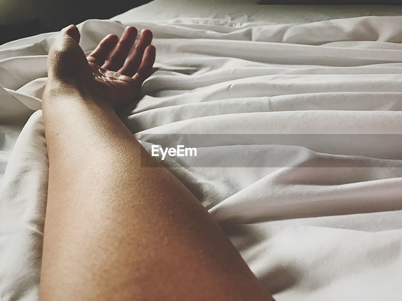 Cropped hand of woman lying on bed