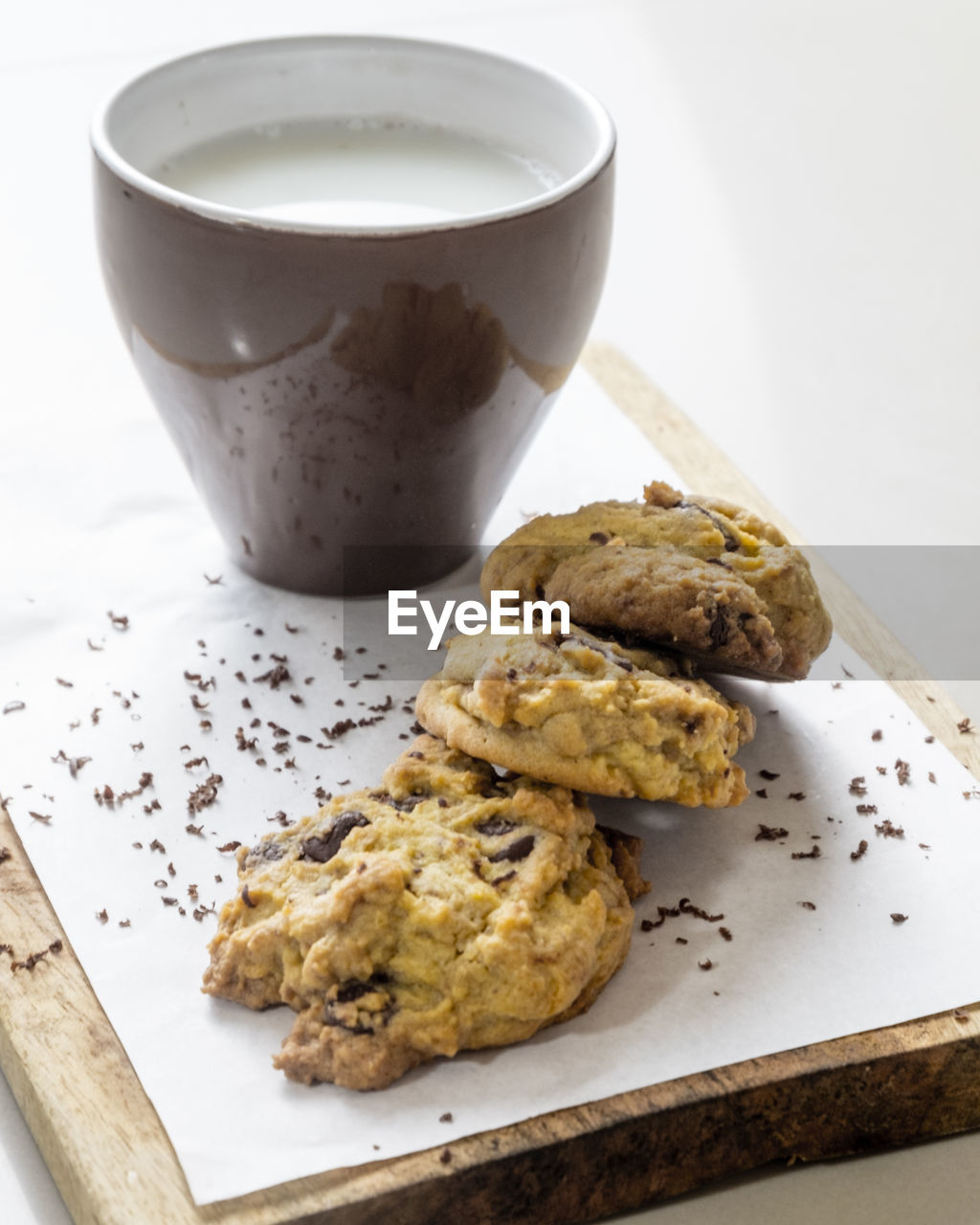 Close-up of cookies and milk in mug on cutting board