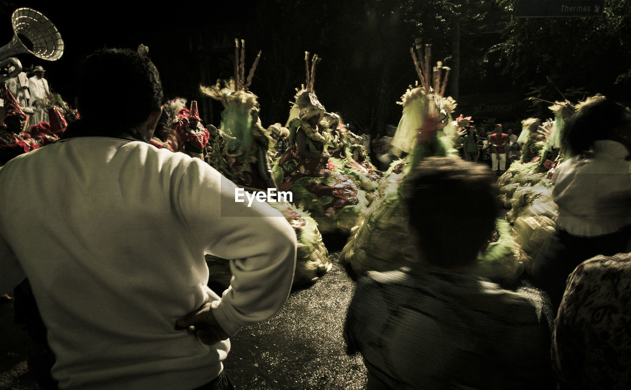 REAR VIEW OF PEOPLE STANDING IN FRONT OF A GROUP OF TREE