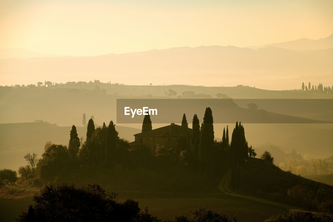 Silhouette trees and mountains against sky during sunset