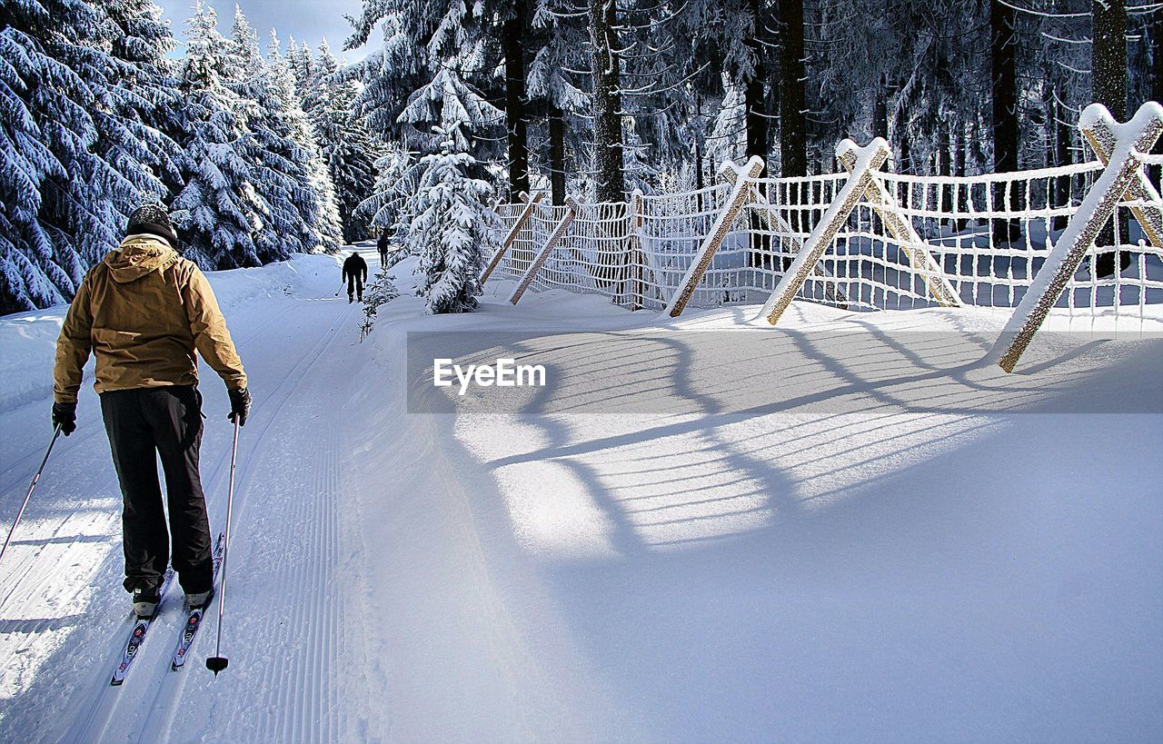 Rear view of man skiing on snow in forest