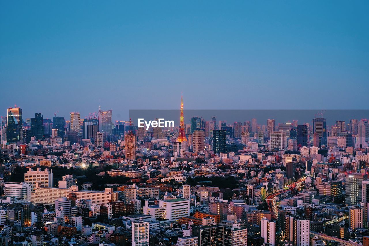 Aerial view of modern buildings against clear sky against sunset