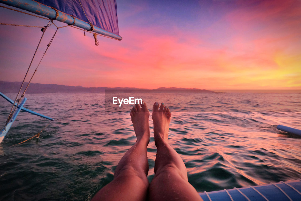 Female relaxing on a sailboat in front of the sunset