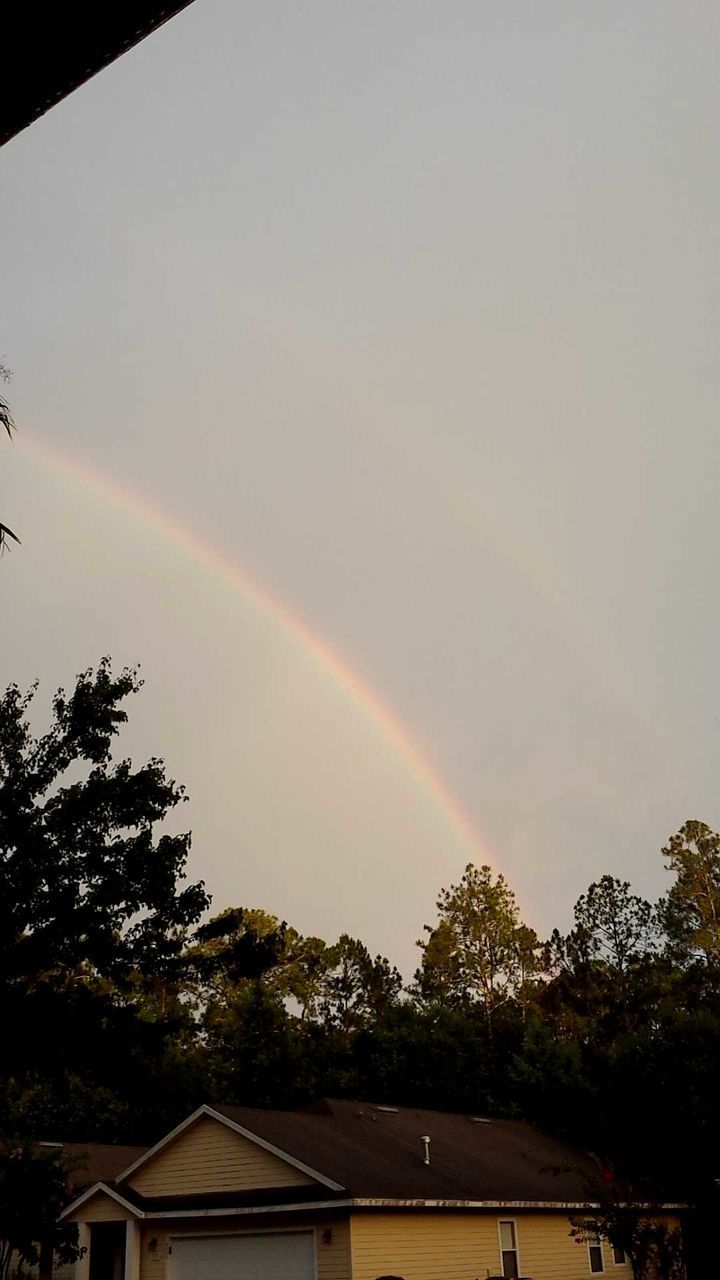 Exterior of house against rainbow in sky at sunset