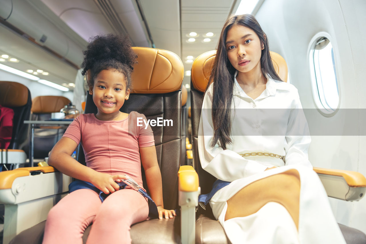 A happy little child and woman are seated in a passenger airliner.