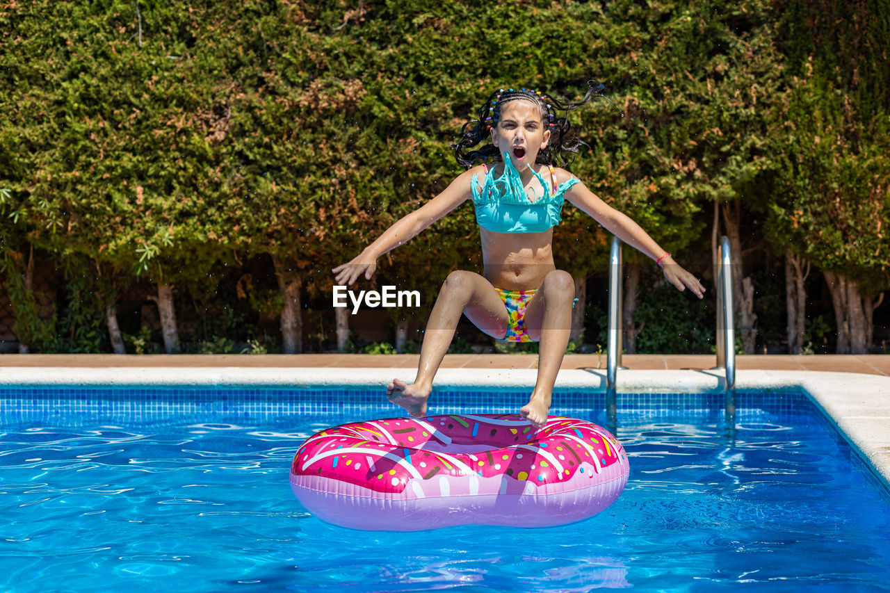 Lttle girl jumping on a rubber ring into a pool