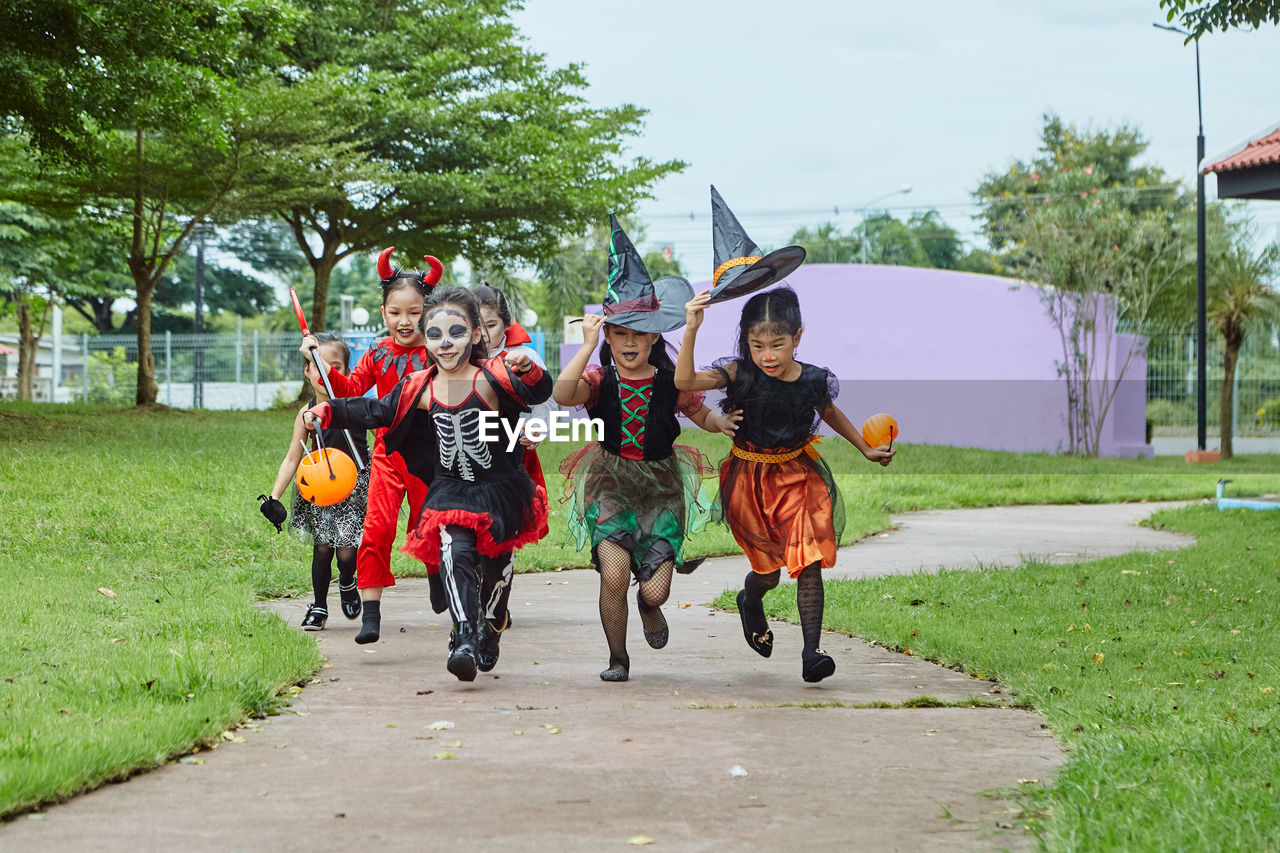 Girls in costumes running on footpath during halloween