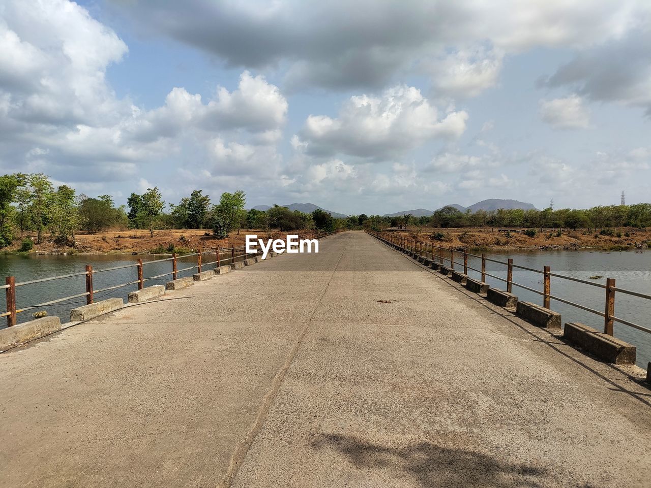 sky, cloud, walkway, water, shore, nature, boardwalk, sea, coast, the way forward, transportation, architecture, environment, landscape, tree, diminishing perspective, land, no people, road, scenics - nature, horizon, travel, vanishing point, day, travel destinations, outdoors, beach, beauty in nature, bridge, railing, plant, footpath, city, tranquility, built structure, tourism, pier, waterway, tranquil scene, street, holiday