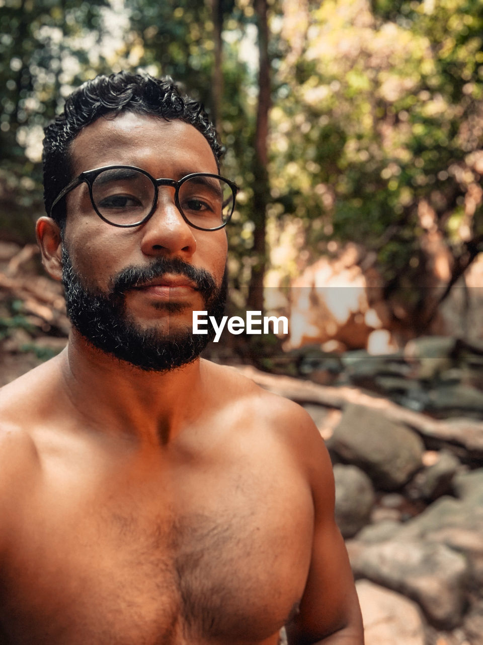 Portrait of shirtless man standing in forest