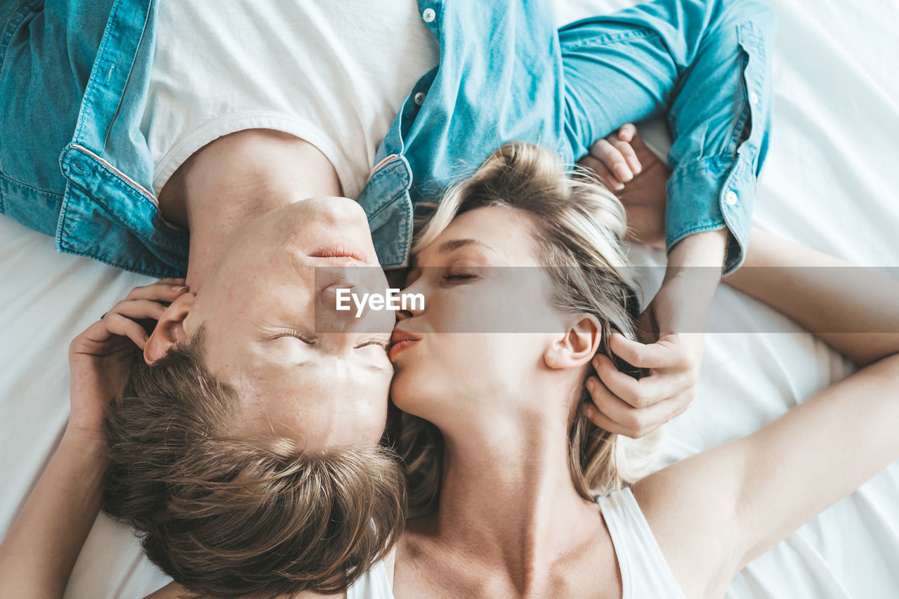 High angle view of couple embracing while lying on bed