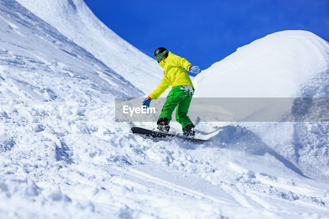 Low angle view of young man skiing on snowcapped mountains during winter