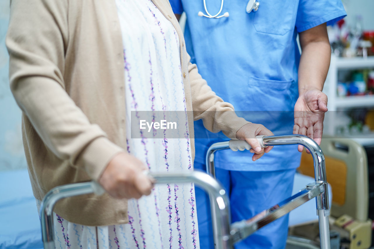 Midsection of nurse standing by patient with mobility walker