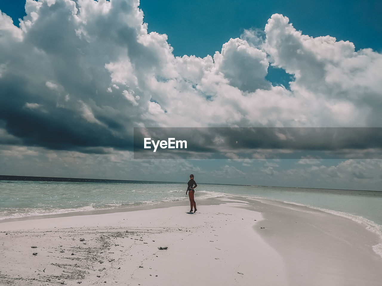 Woman standing at beach against sky