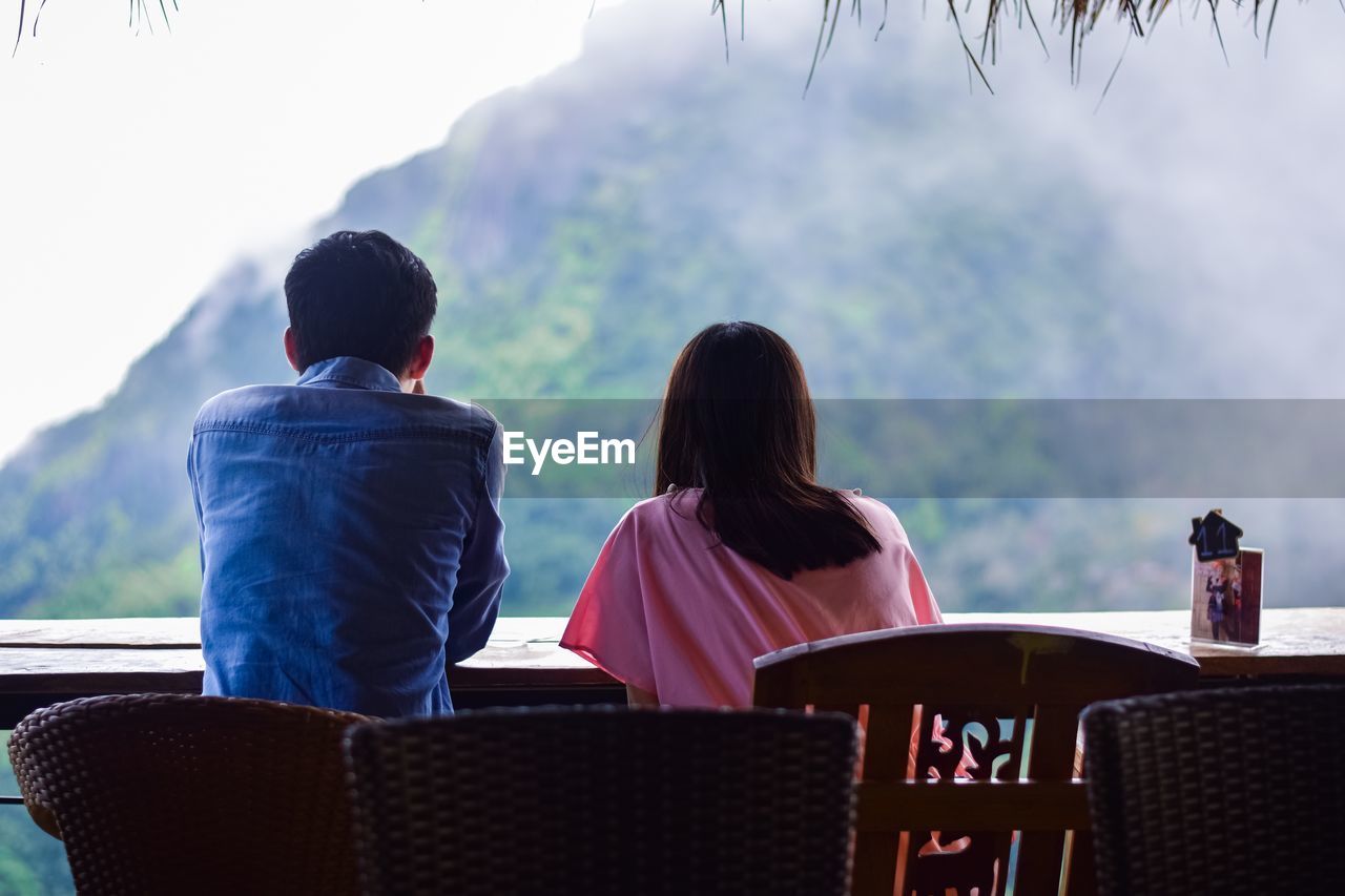 Couple sitting on chair against mountain