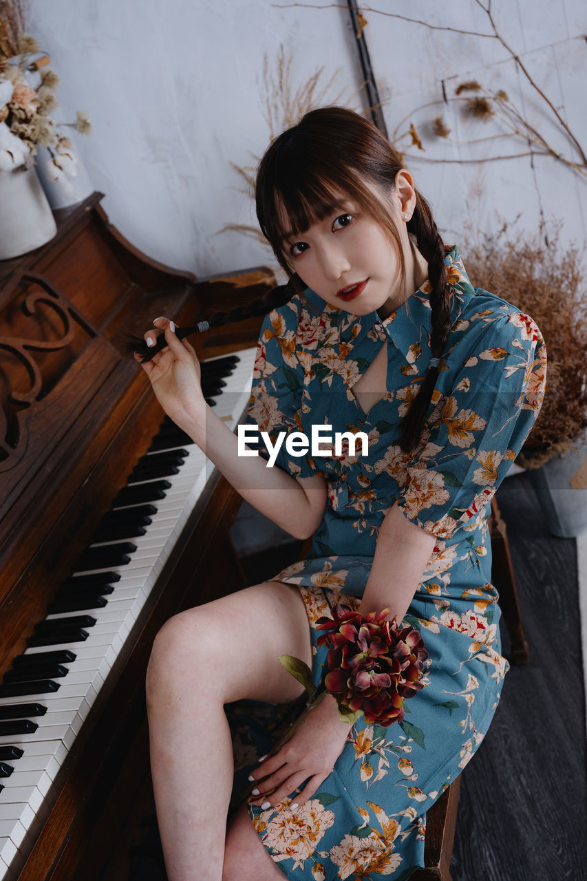 portrait of young woman playing piano at home