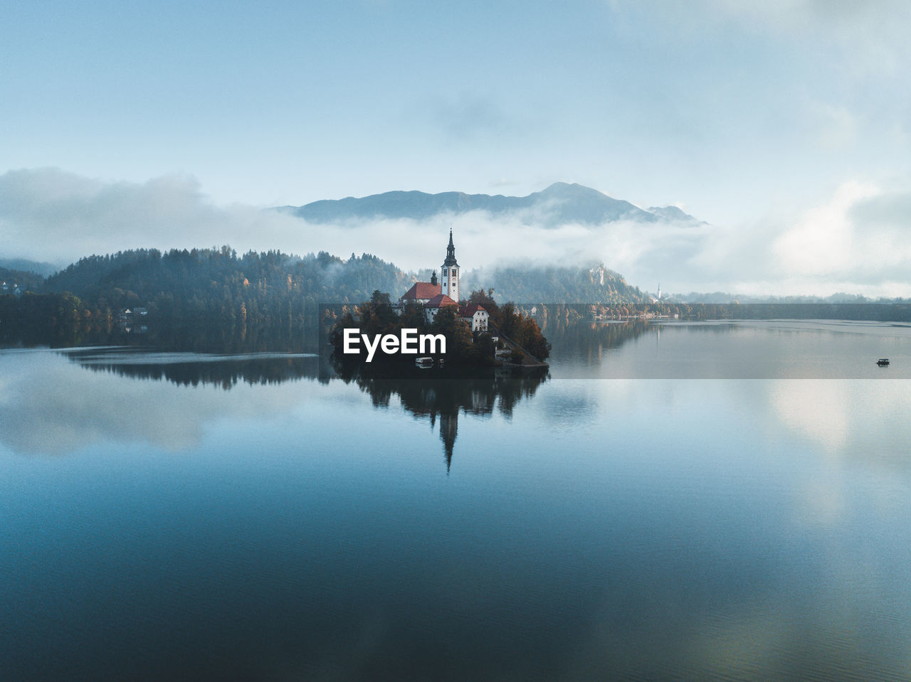 Scenic view of lake by building against sky. fantastic sunrise with mist in bled, slovenia