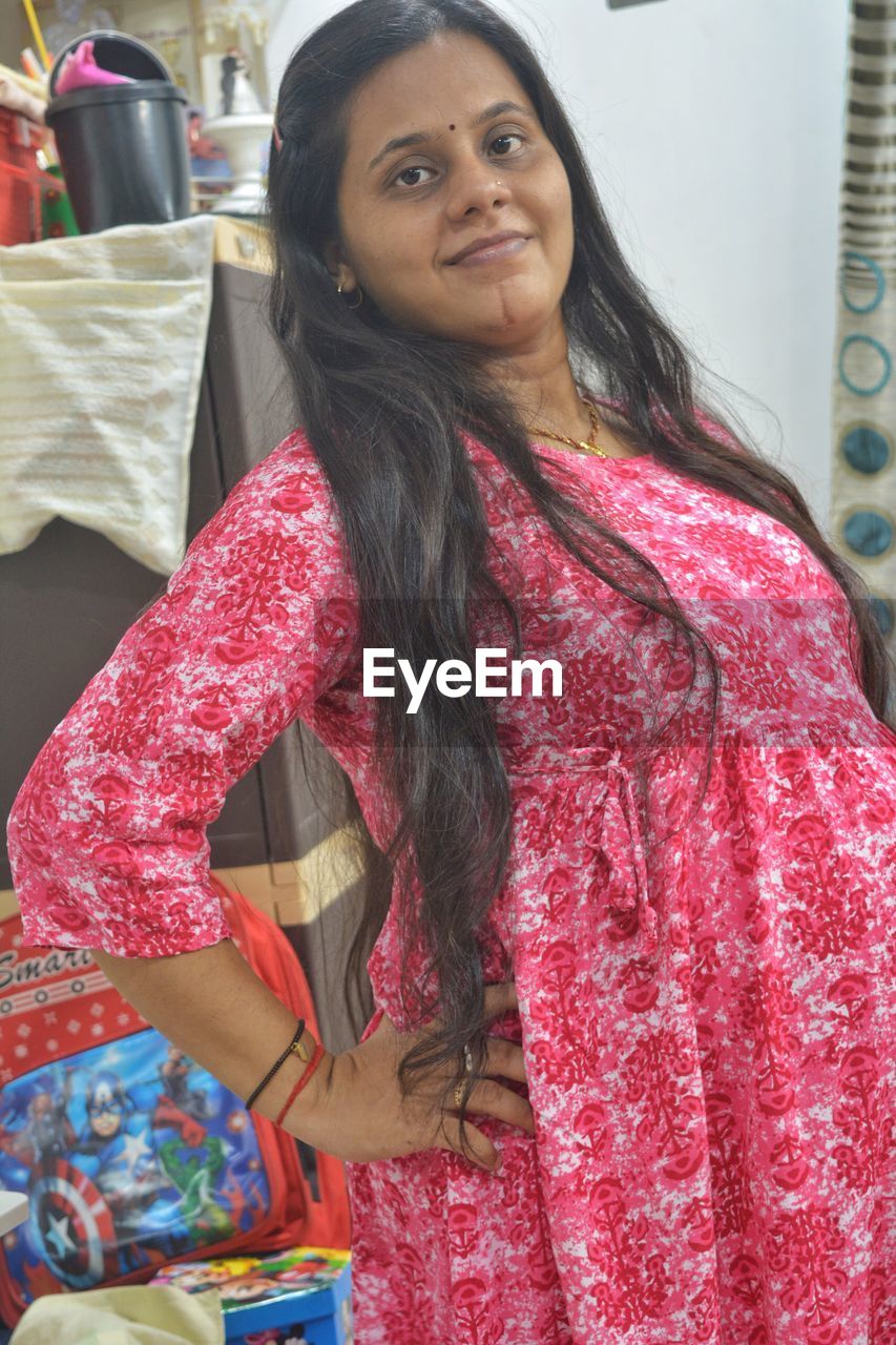 one person, women, portrait, adult, looking at camera, smiling, clothing, long hair, indoors, happiness, hairstyle, standing, waist up, black hair, lifestyles, emotion, sari, three quarter length, female, retail, traditional clothing, fashion, store, front view, young adult, business, pink, business finance and industry, looking, person, arts culture and entertainment, photo shoot, cheerful, pattern, leisure activity, shopping