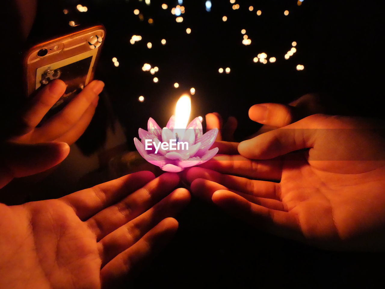 CLOSE-UP OF HAND HOLDING LIT CANDLE