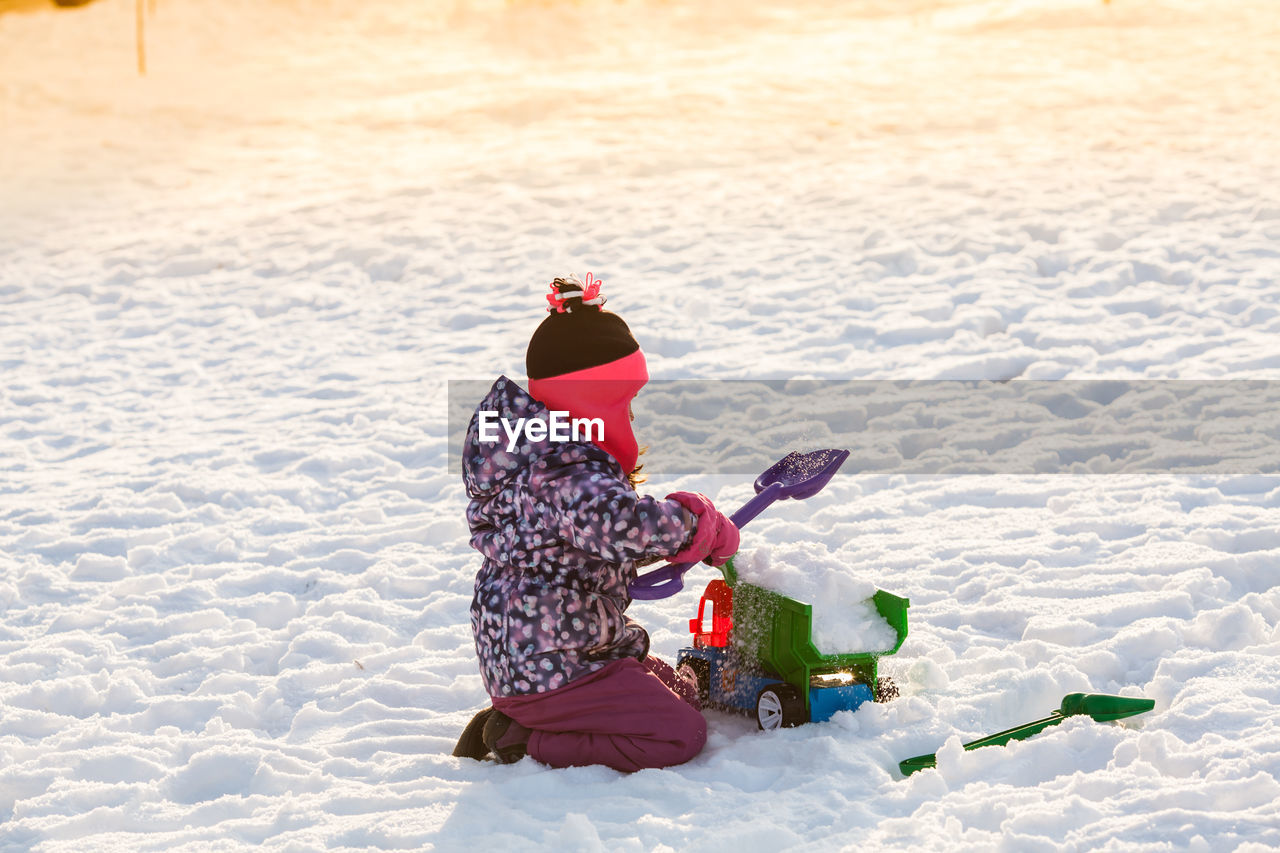 REAR VIEW OF GIRL WITH UMBRELLA ON SNOW