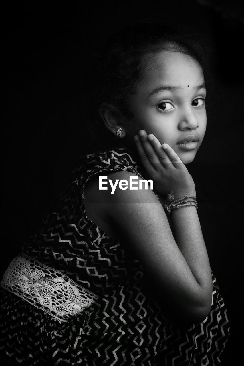 Portrait of cute girl against black background