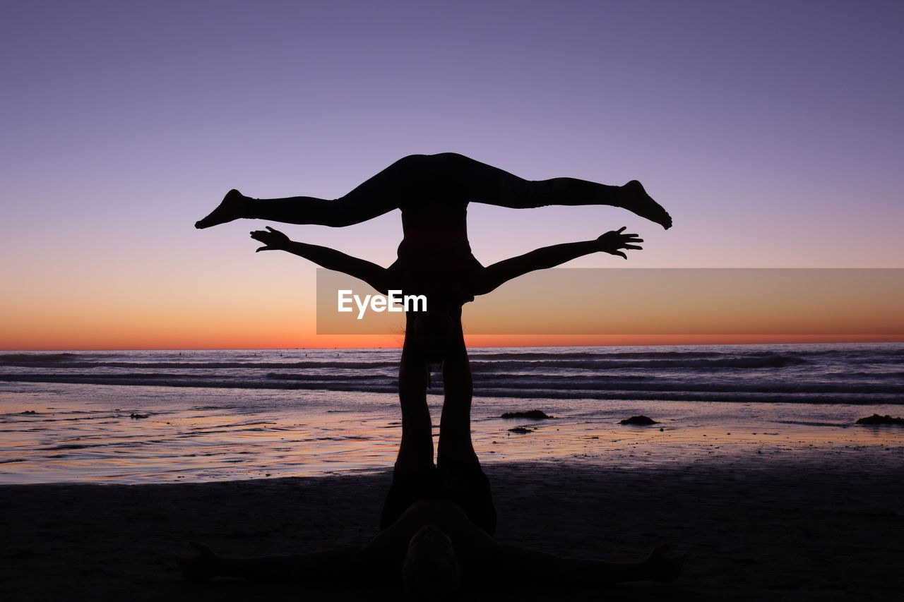 Silhouette couple at beach against clear sky during sunset