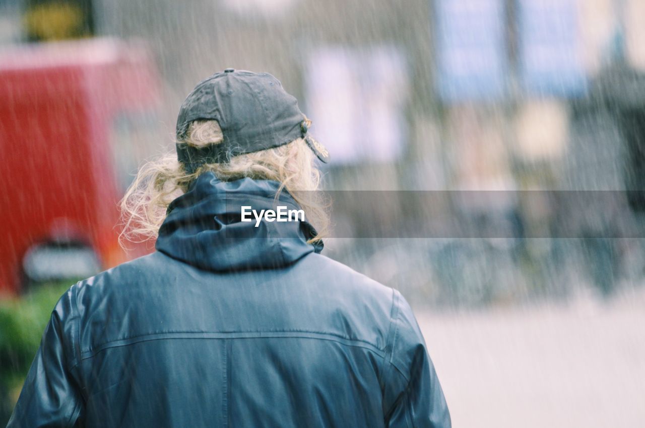 Rear view of man walking outdoors during rainfall