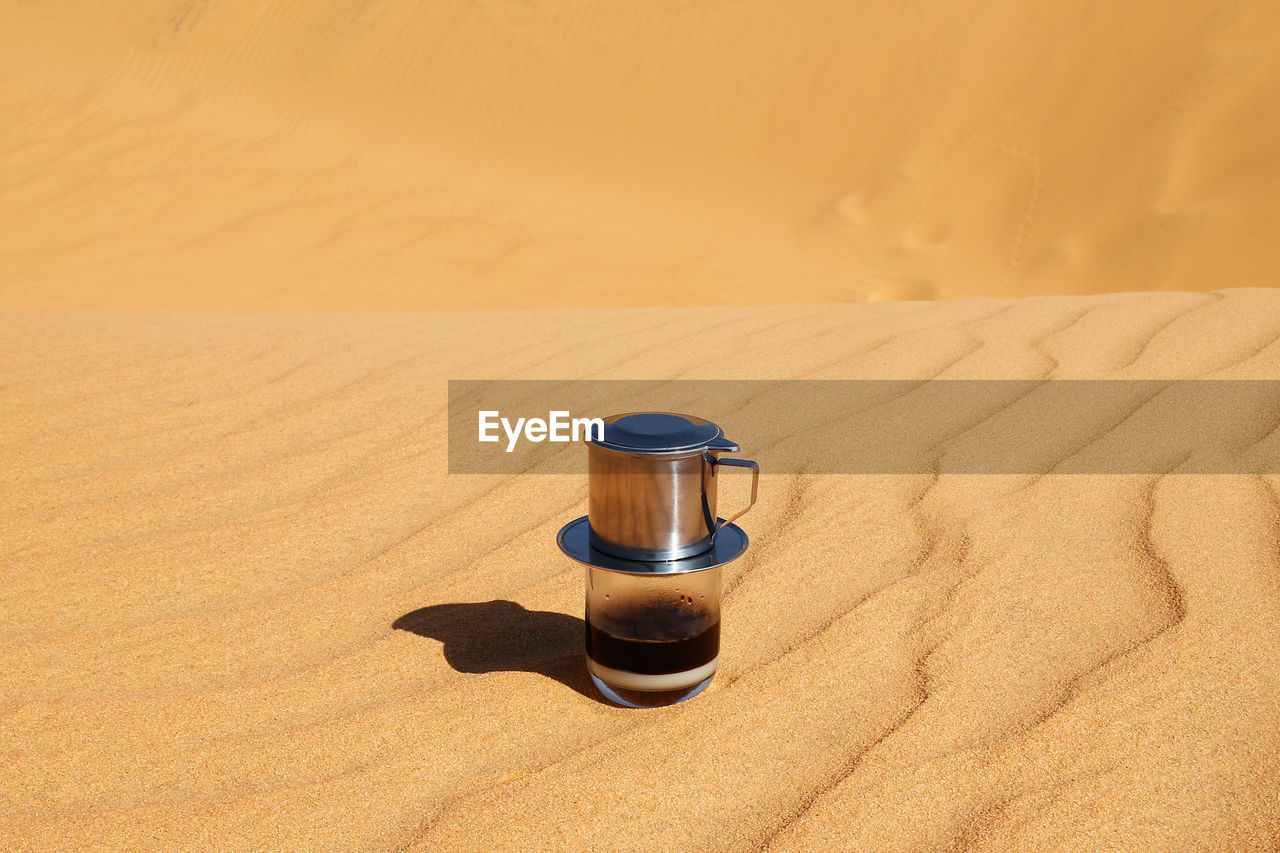 Drip black coffee in vietnamese style with condensed milk on a red sand. 