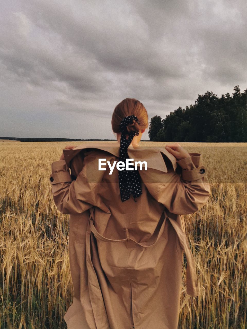 Rear view of woman standing on field against sky