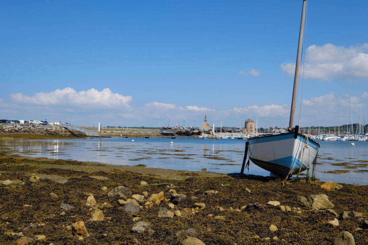 Sailboats moored on beach against sky