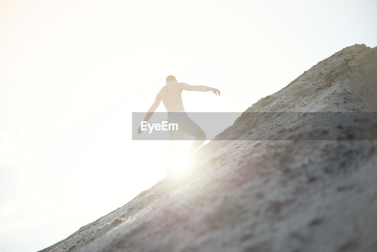 Low angle view of person on rock against sky