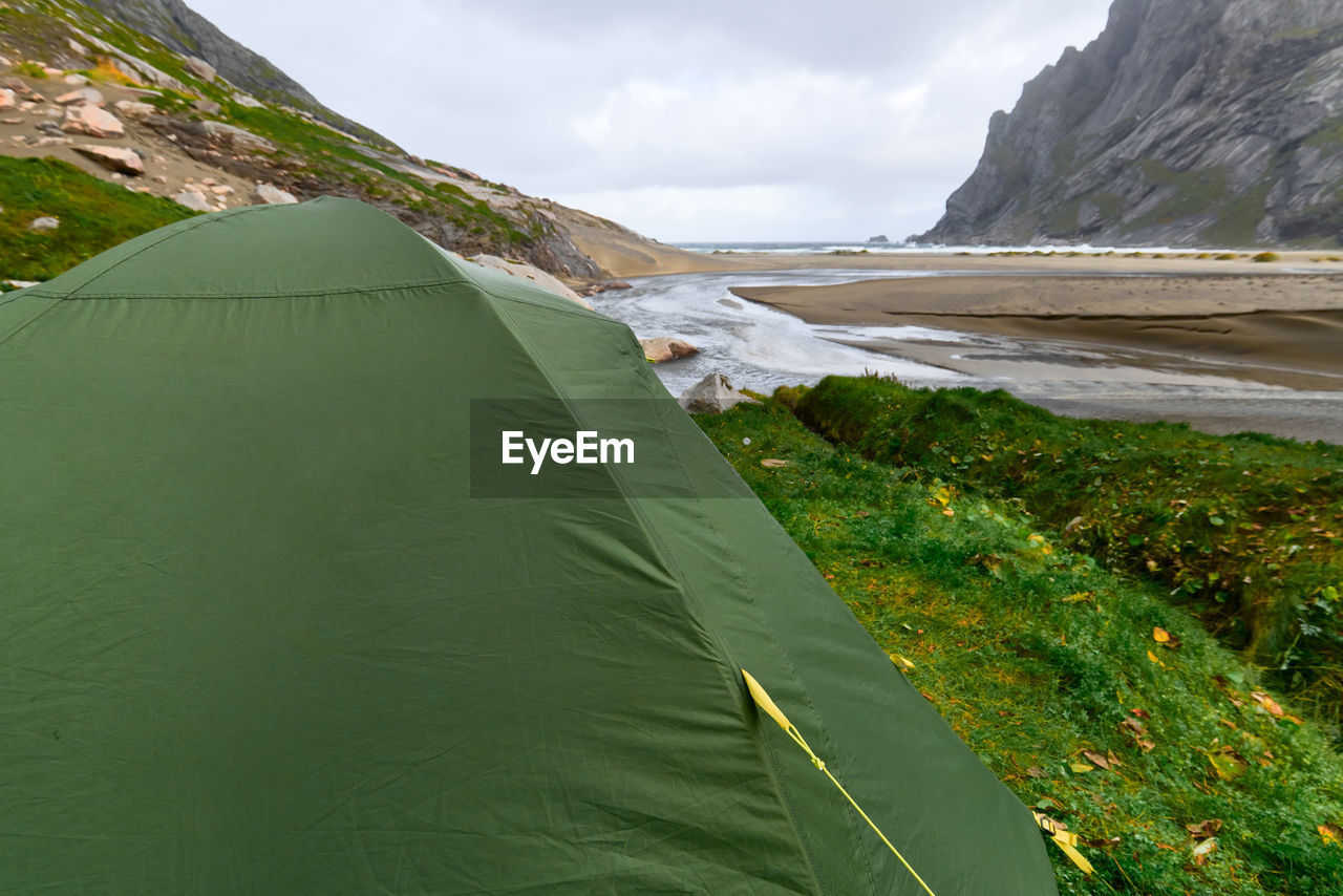 Green tent on a green grass hill at bunes beach with view over the valley in lofoten norway