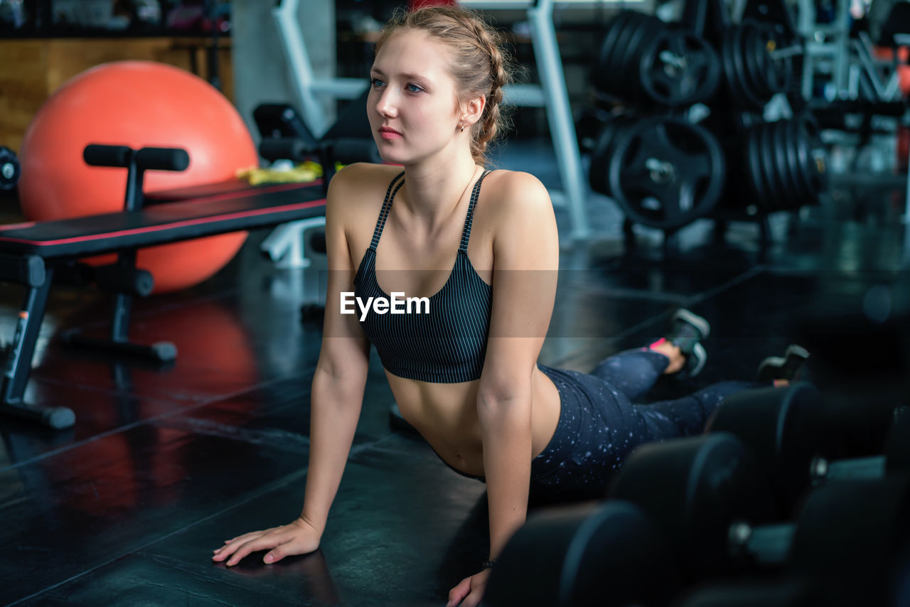 Young beautiful woman stretching and warming up before workout in fitness gym