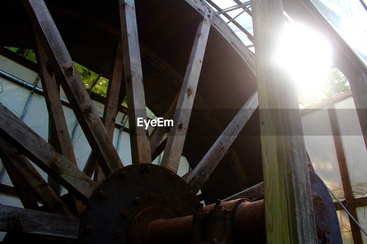 Low angle view of water wheel against bright sun