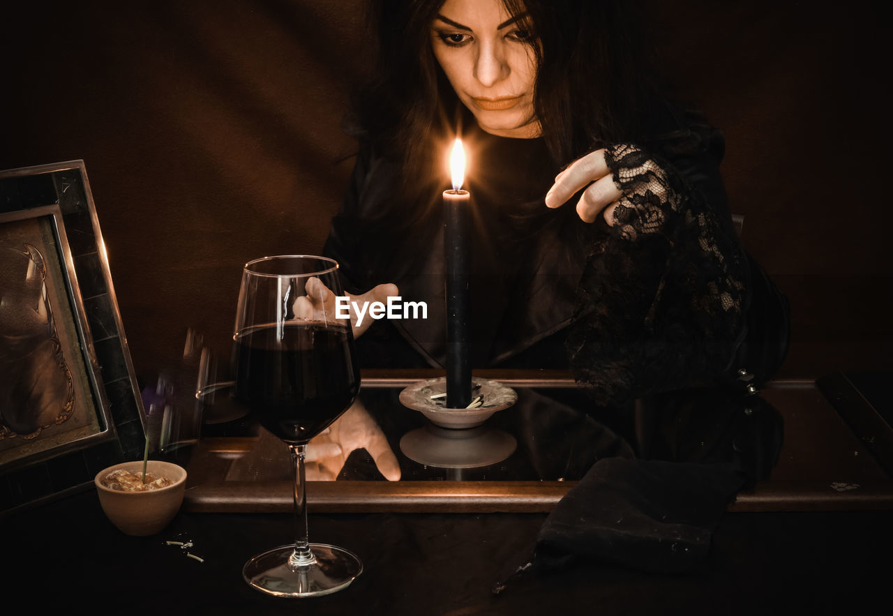 Midsection of woman holding wine glass while making magic ritual 