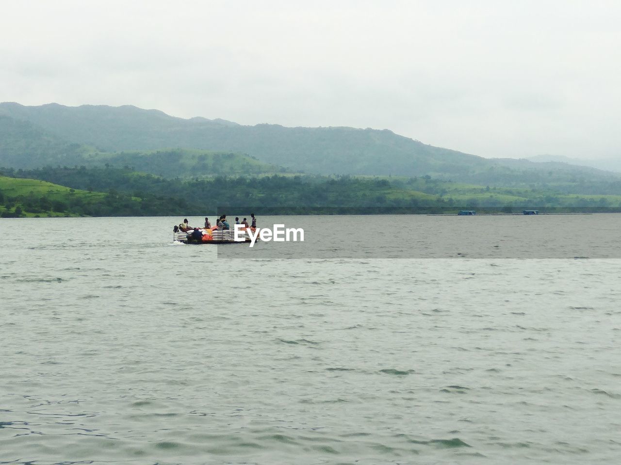 BOAT ON CALM LAKE AGAINST MOUNTAIN RANGE